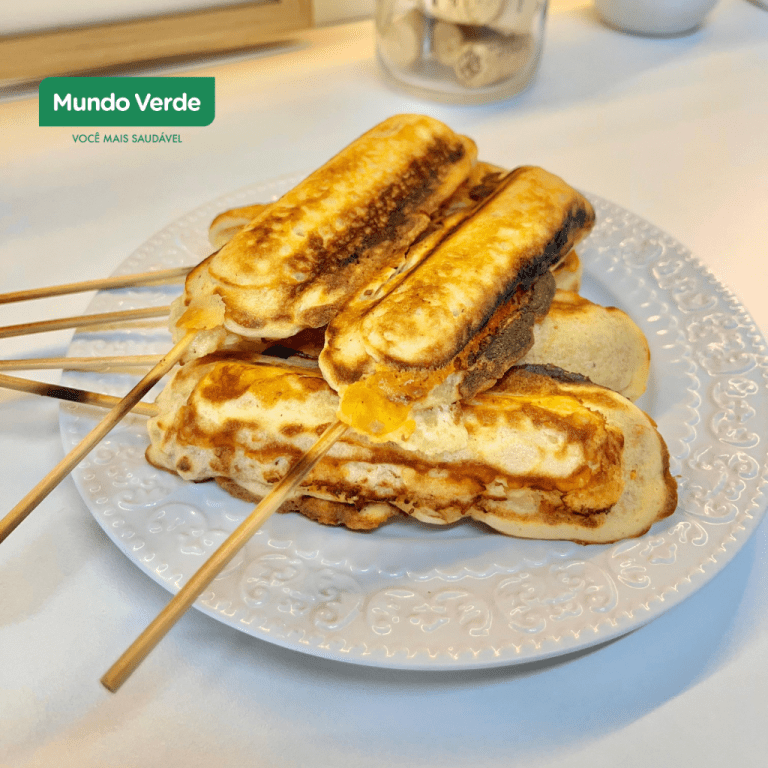 Prato branco com vários crepes proteicos no palito, dourados e recheados, dispostos sobre uma mesa clara. No canto superior esquerdo aparece o logo da Mundo Verde.